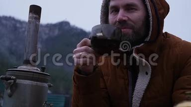 留胡子的人正在山谷的旅游营地喝茶。 在寒冷的季节旅行作为一种生活方式。 慢慢慢慢